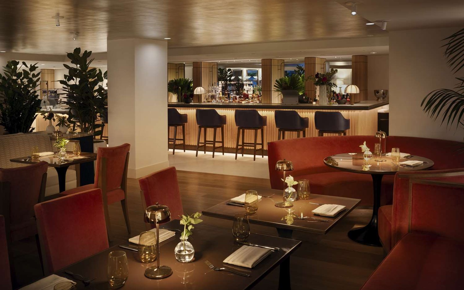 Costa Covo Osteria at ground level: red velvet banquettes, candlelit round tables, the bar behind