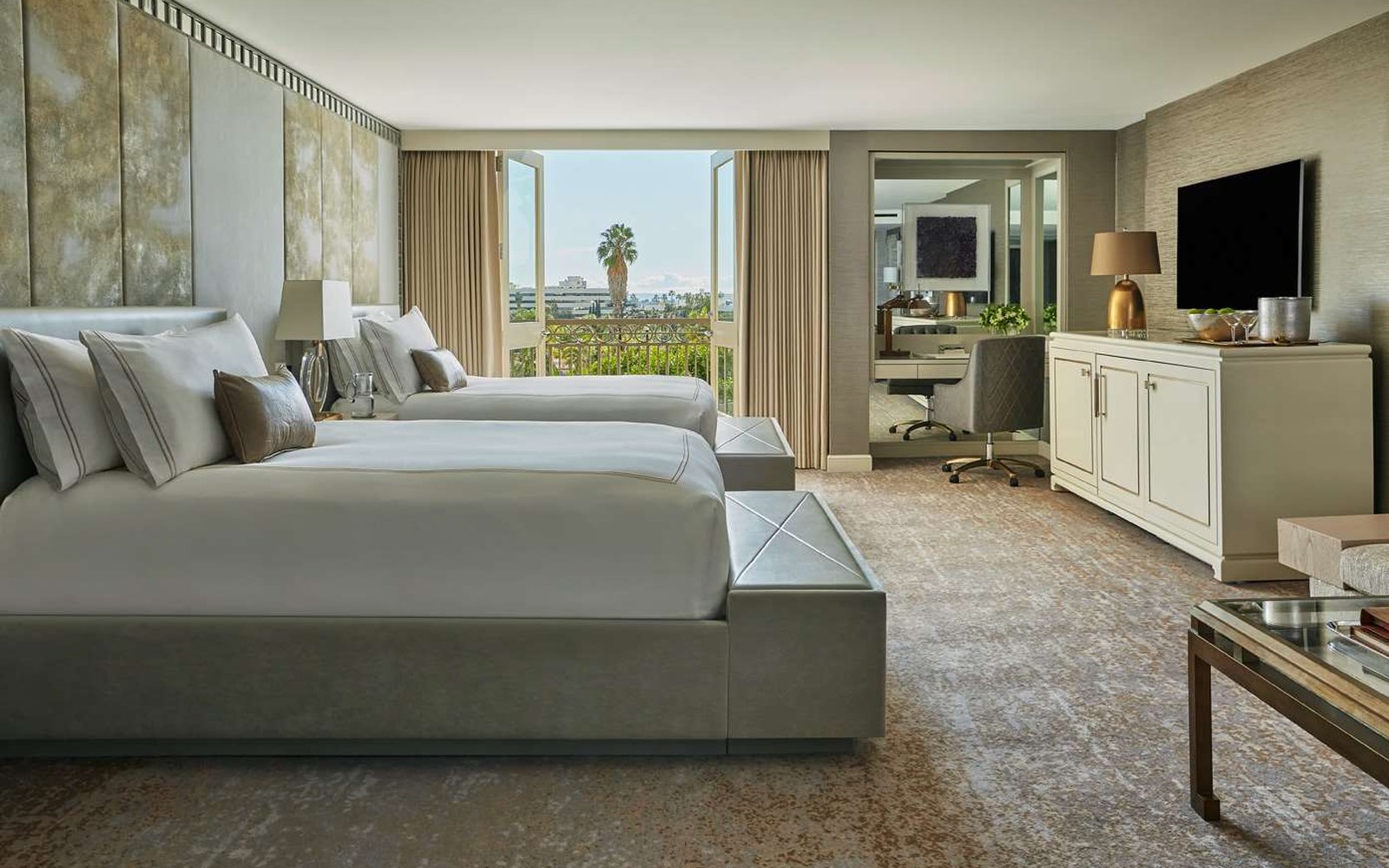 A two-double suite: the glass doors open onto a private balcony, with a separate desk alcove to the side