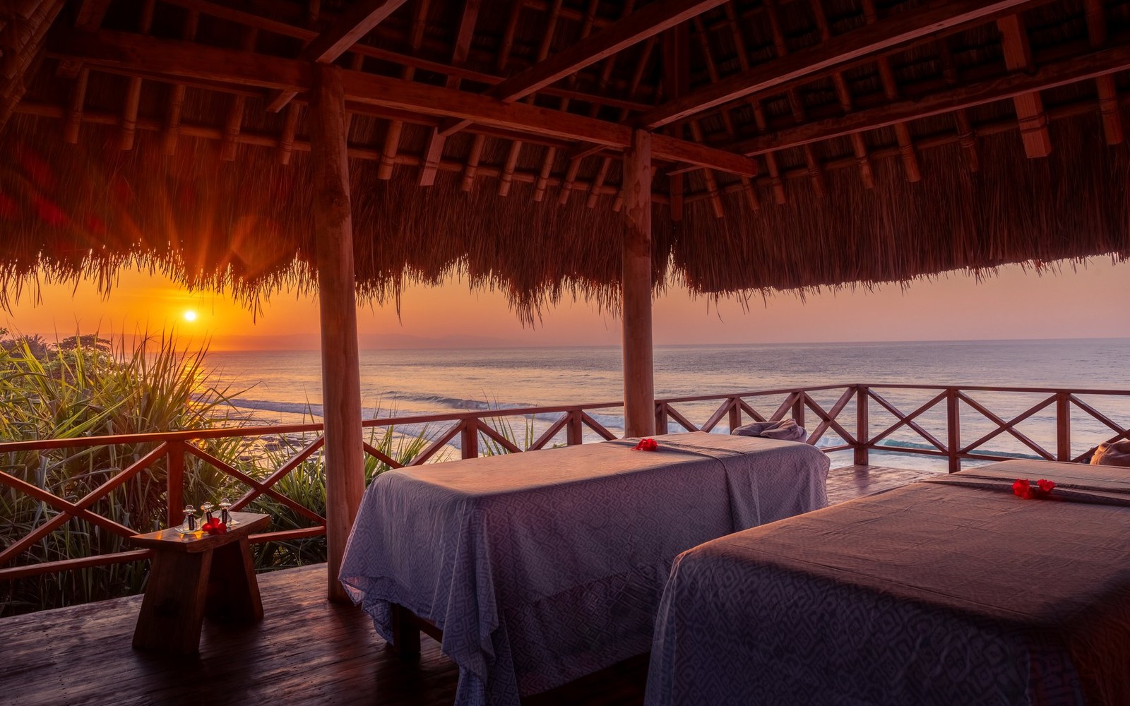 The massage platform at Nihioka: two beds under thatch, open to the sea, late afternoon light coming in low