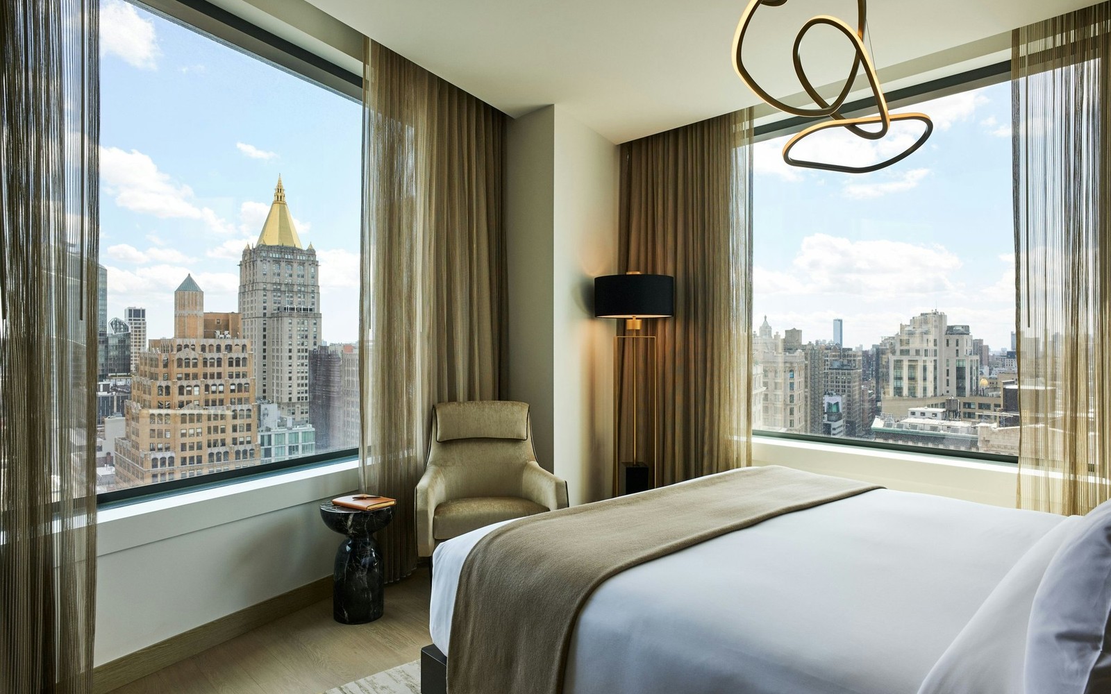 A high-floor guest room: glass across the full wall, the bed facing the city