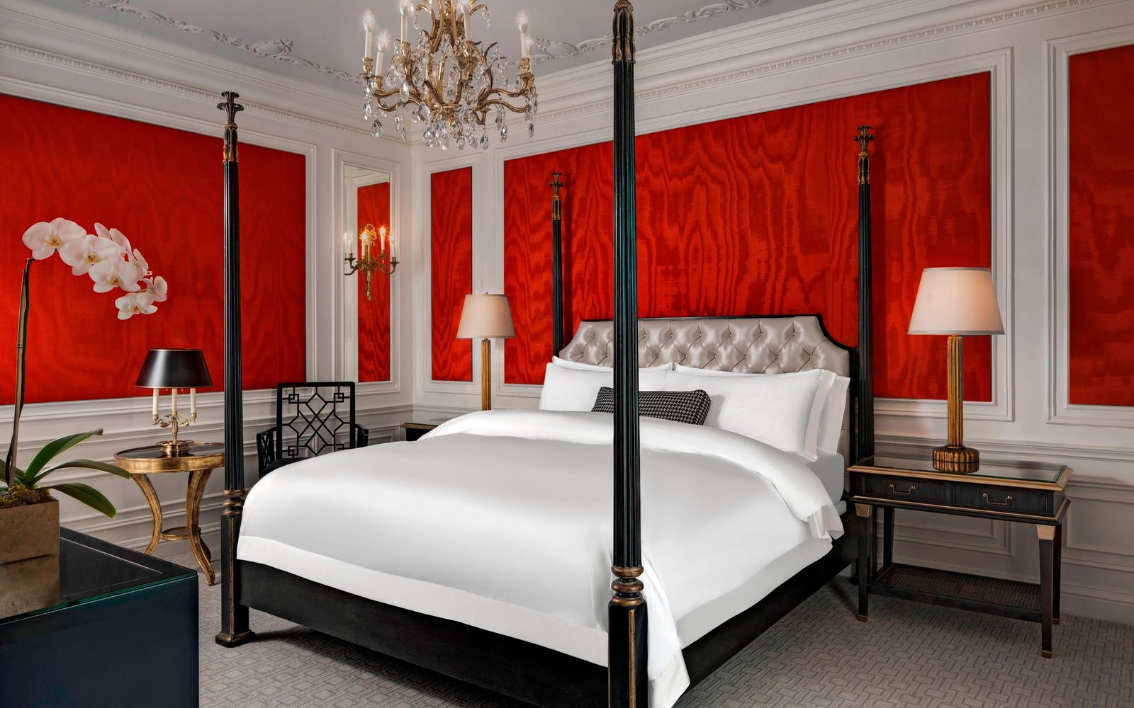 A suite after the renovation: red moir&eacute; walls and a four-poster bed, the Gilded Age thread pulled back out