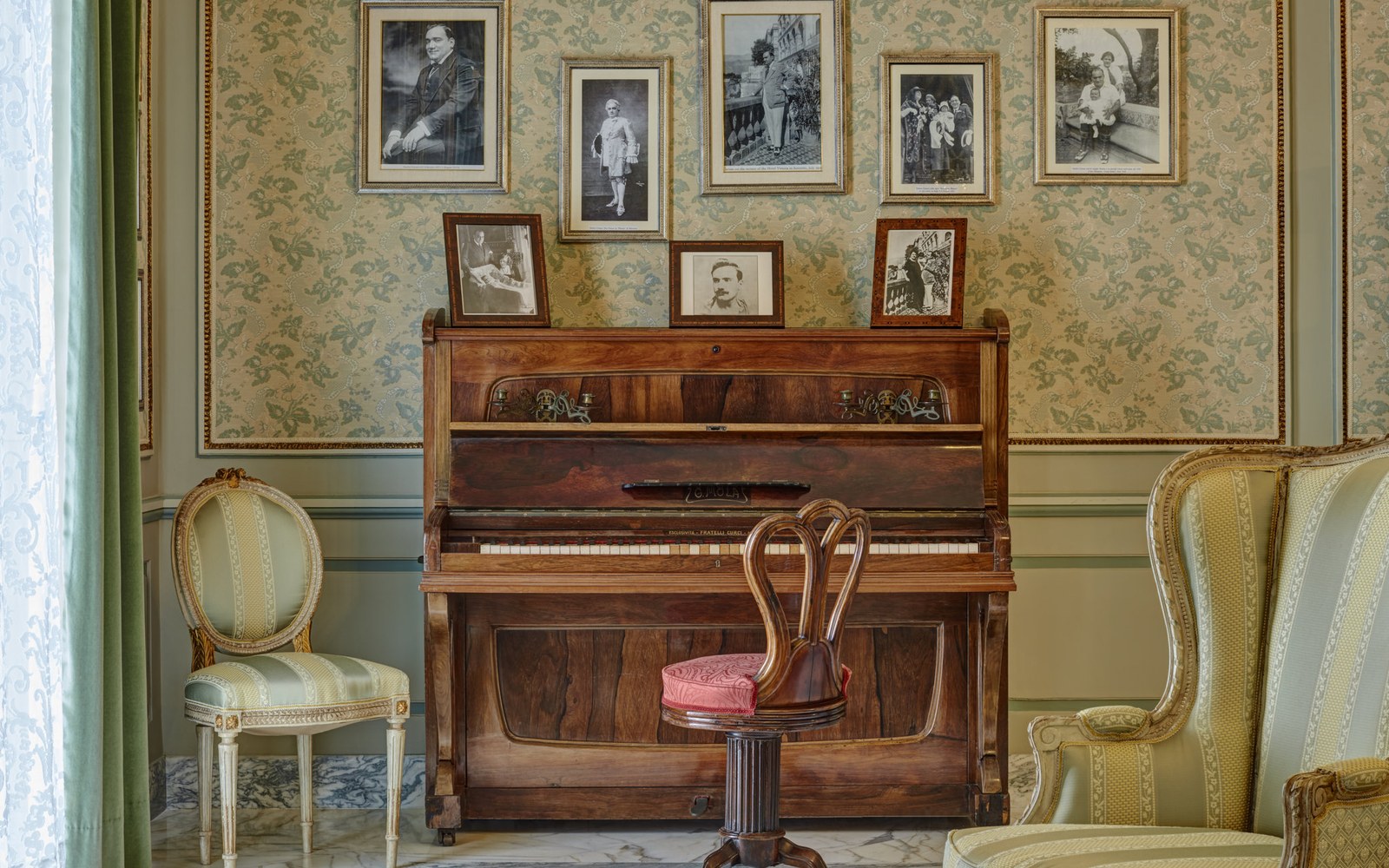An upright piano and a wall of old photographs, from the hotel&rsquo;s own image library