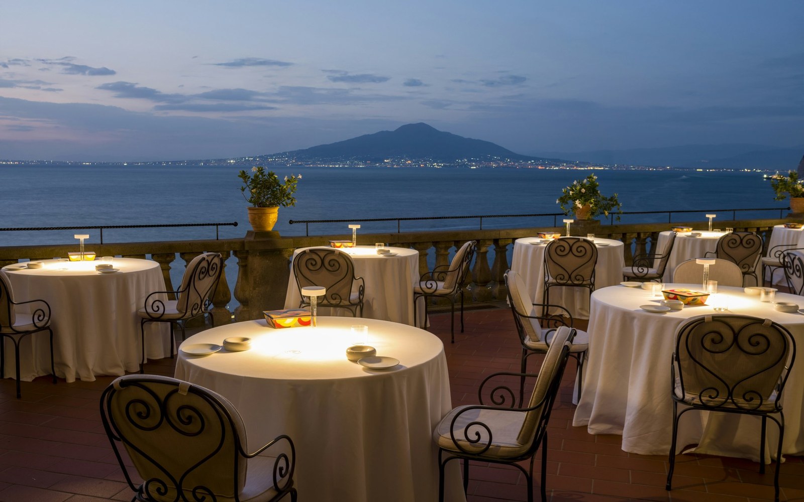 Terrace tables at dusk, with Vesuvius across the water