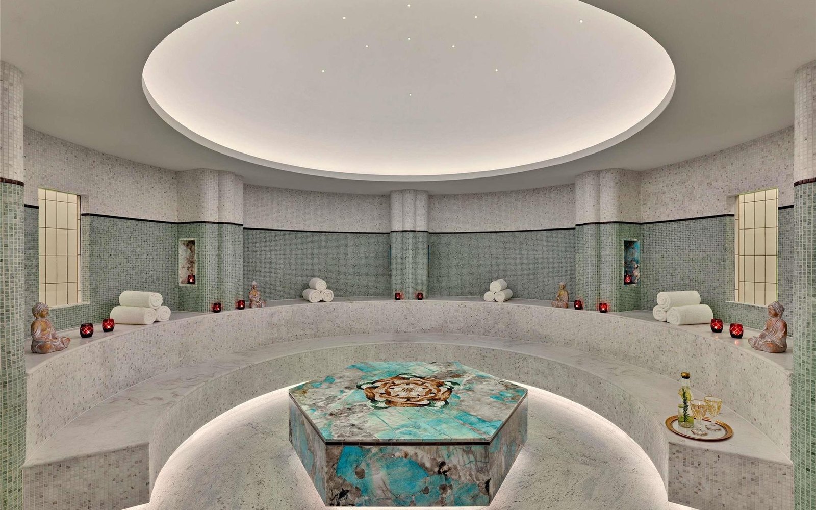 The thermal floor at Tierra Santa Healing House: marble and mosaic pools under a lit ceiling disc