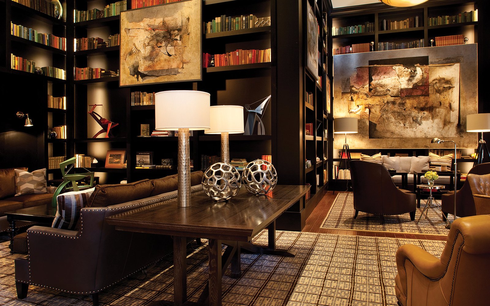 The library: dark book walls, leather armchairs and a long reading table