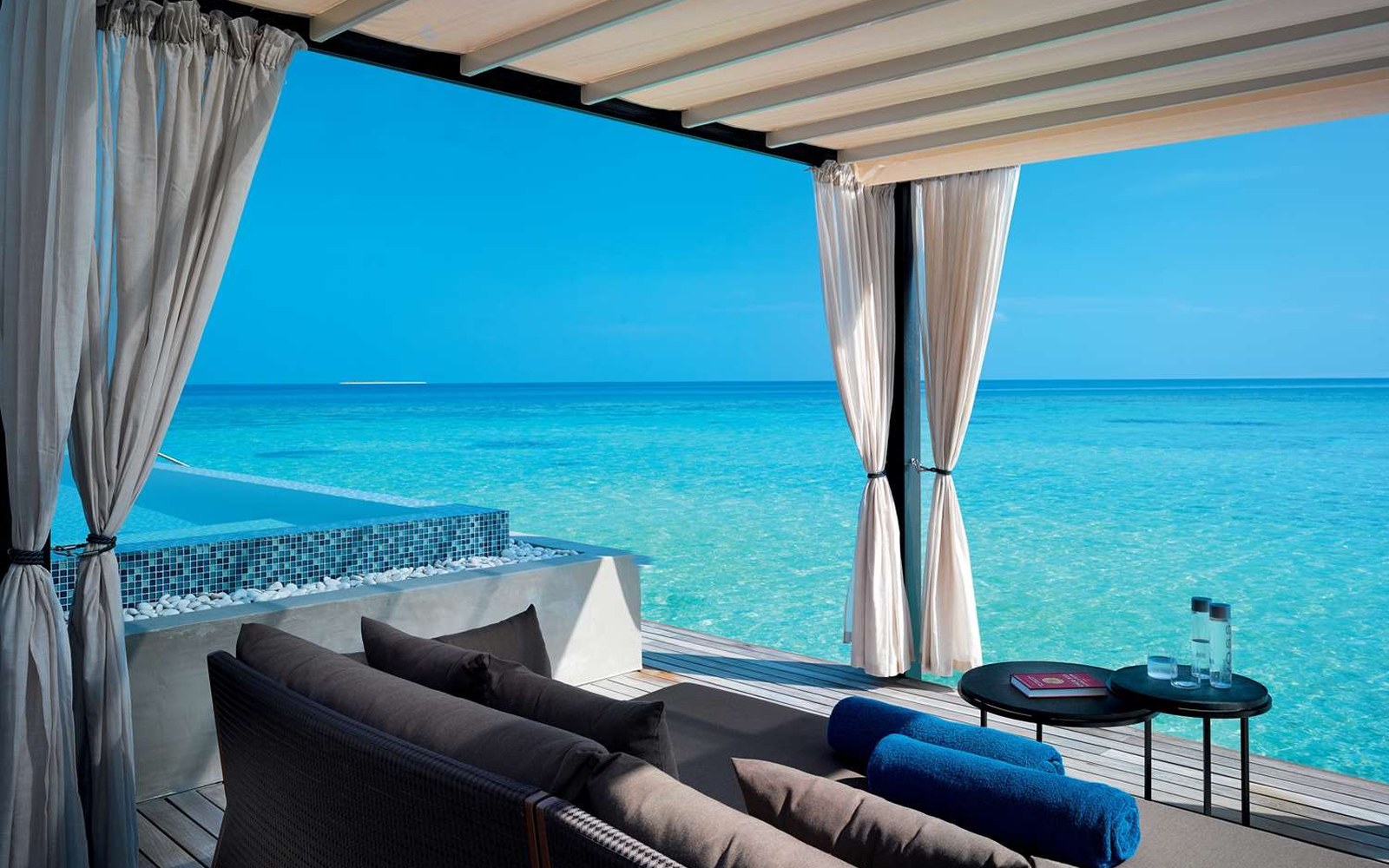 The terrace of a water pool villa: private pool, curtains you can drop, the lagoon directly below the deck